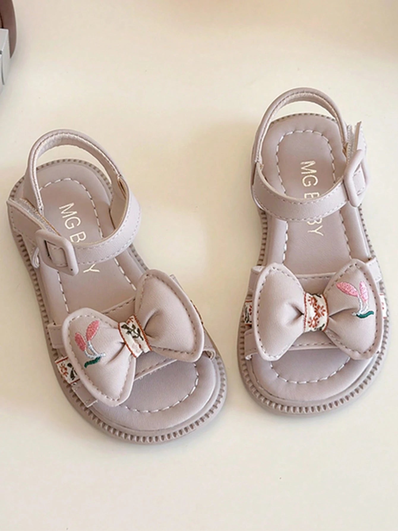 This Beige Children's Sandal Features Multiple Straps And A Bow Decoration, With A Metal Buckle Design For A Refined Touch. The Sole Is In A Brown Color. The Sweet And Cute Style Belongs To The Summer