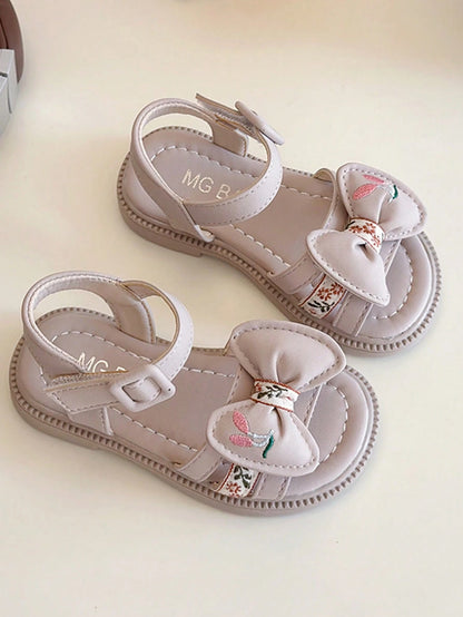 This Beige Children's Sandal Features Multiple Straps And A Bow Decoration, With A Metal Buckle Design For A Refined Touch. The Sole Is In A Brown Color. The Sweet And Cute Style Belongs To The Summer